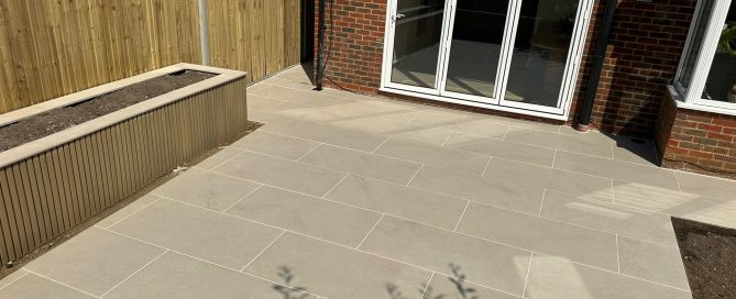 Completed porcelain patio with a raised planter beside a Croydon home