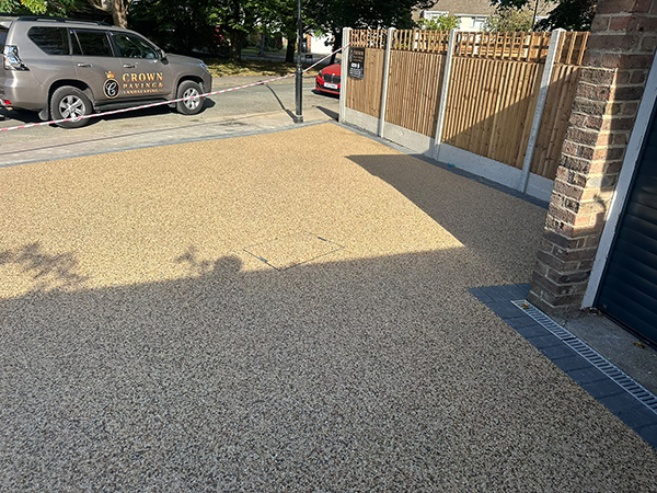 Close view of resin bound driveway surface with timber fencing and dark block edging in Selsdon