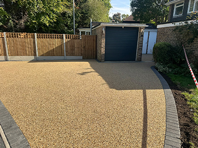 Finished resin bound driveway leading to a garage with block edging and new fencing in Selsdon